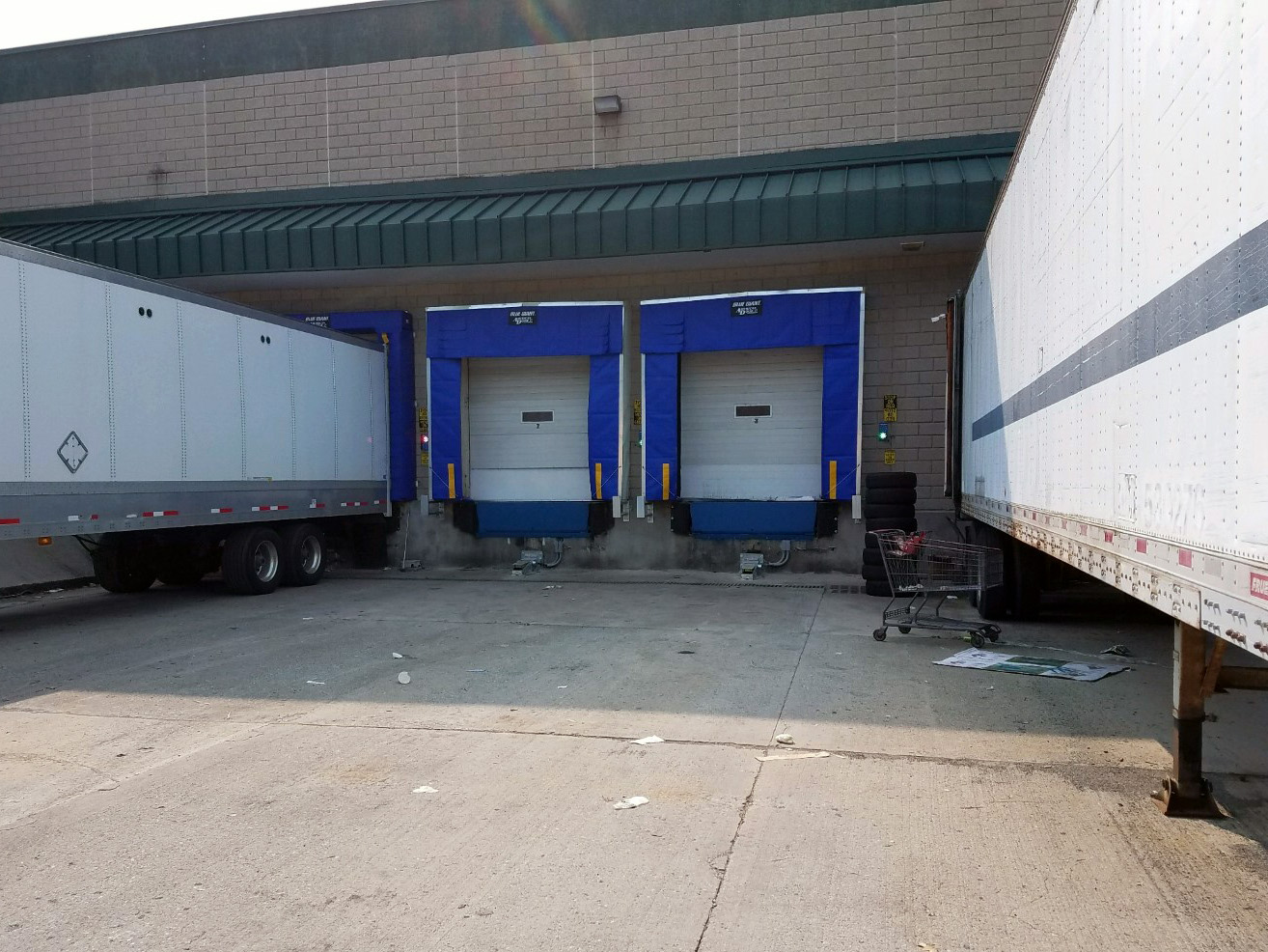 Retractable Dock Shelter with sectional door and hydraulic vehicle restraint system with trucks in dock